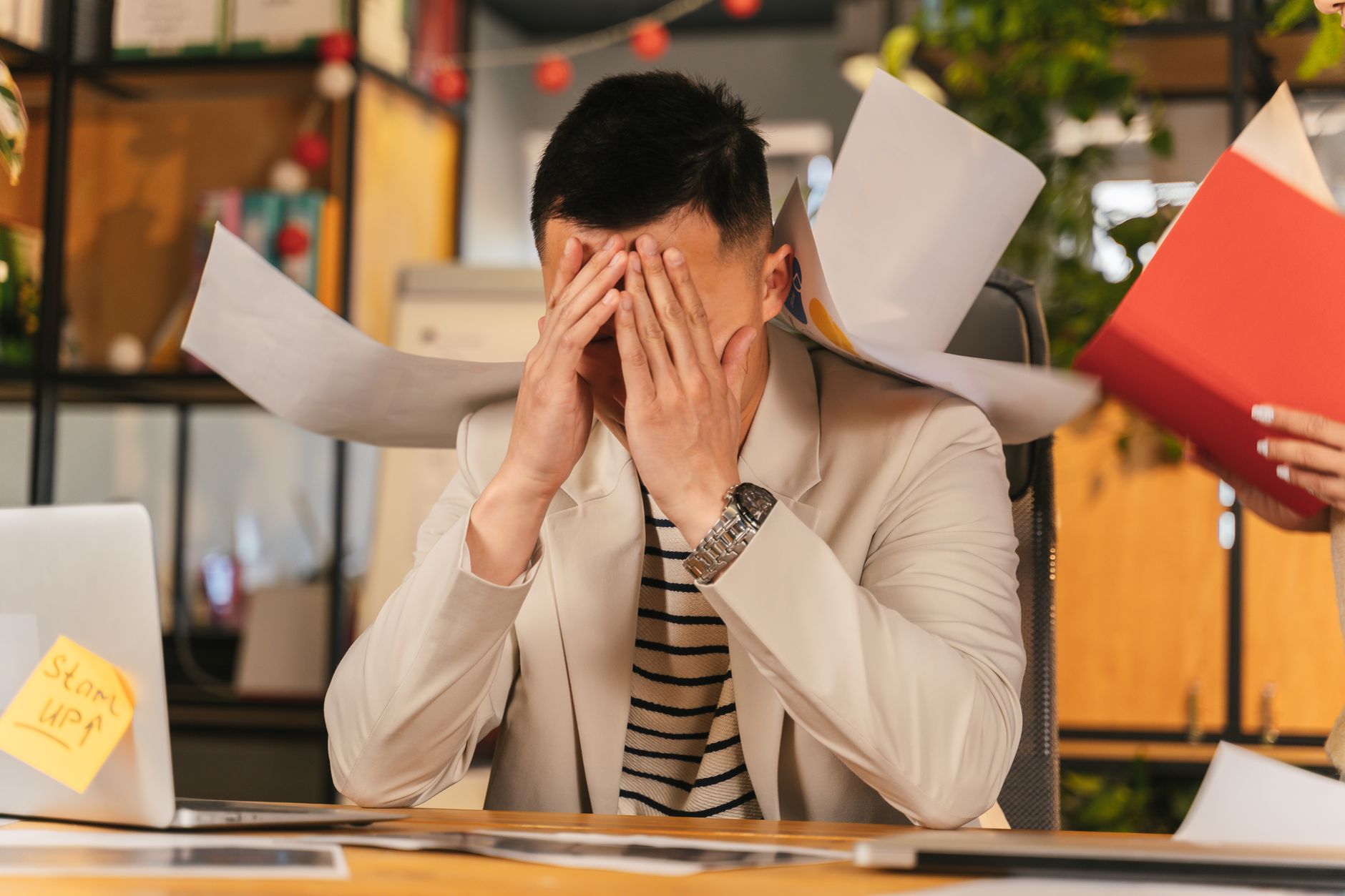 多くの書類に囲まれて業務に追われるオフィスワーカー